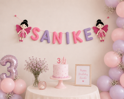 Birthday celebration setup with 'SANIKE' name banner, pink and purple balloons.