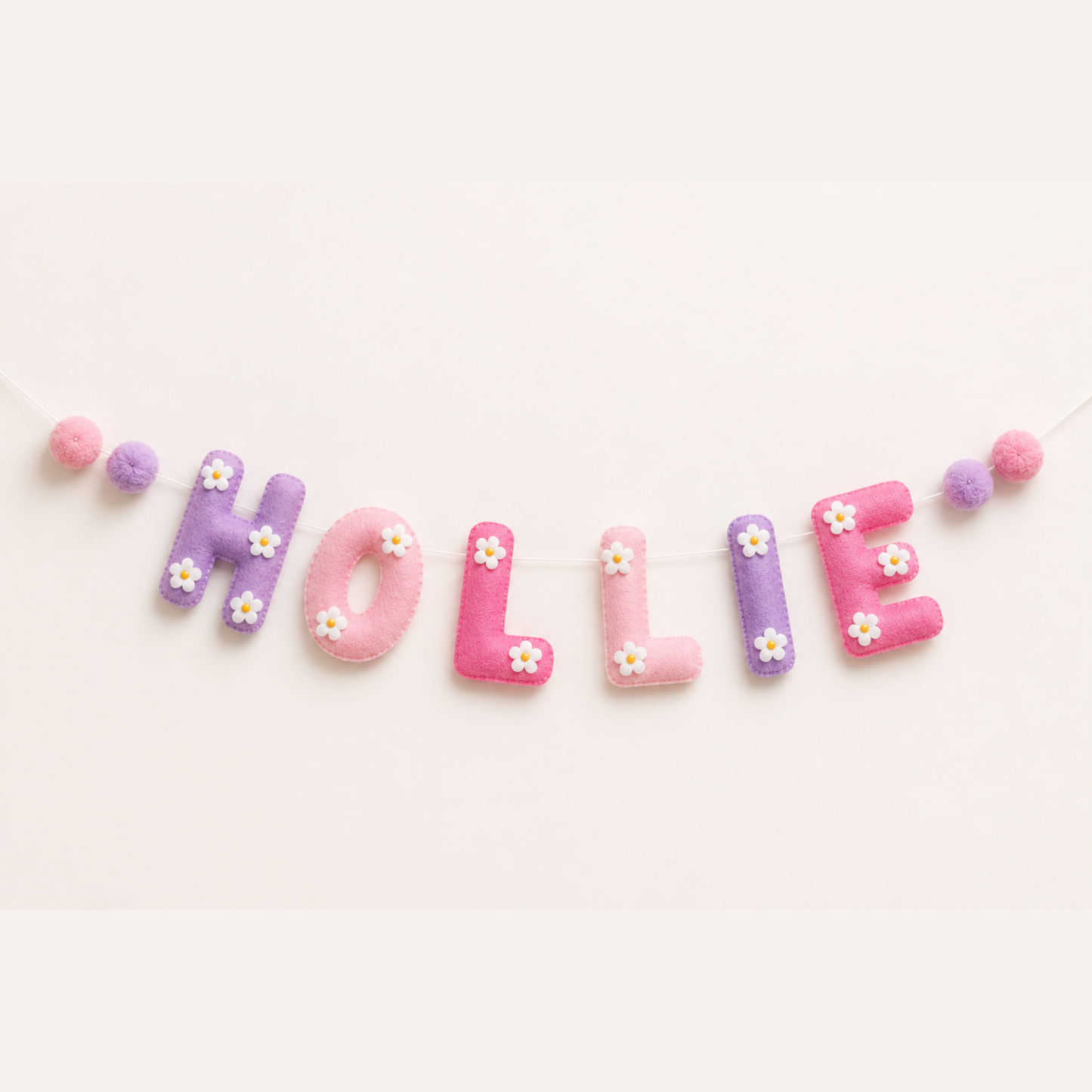 Pastel-colored letters spelling 'HOLLIE' on a light pink background name garland.