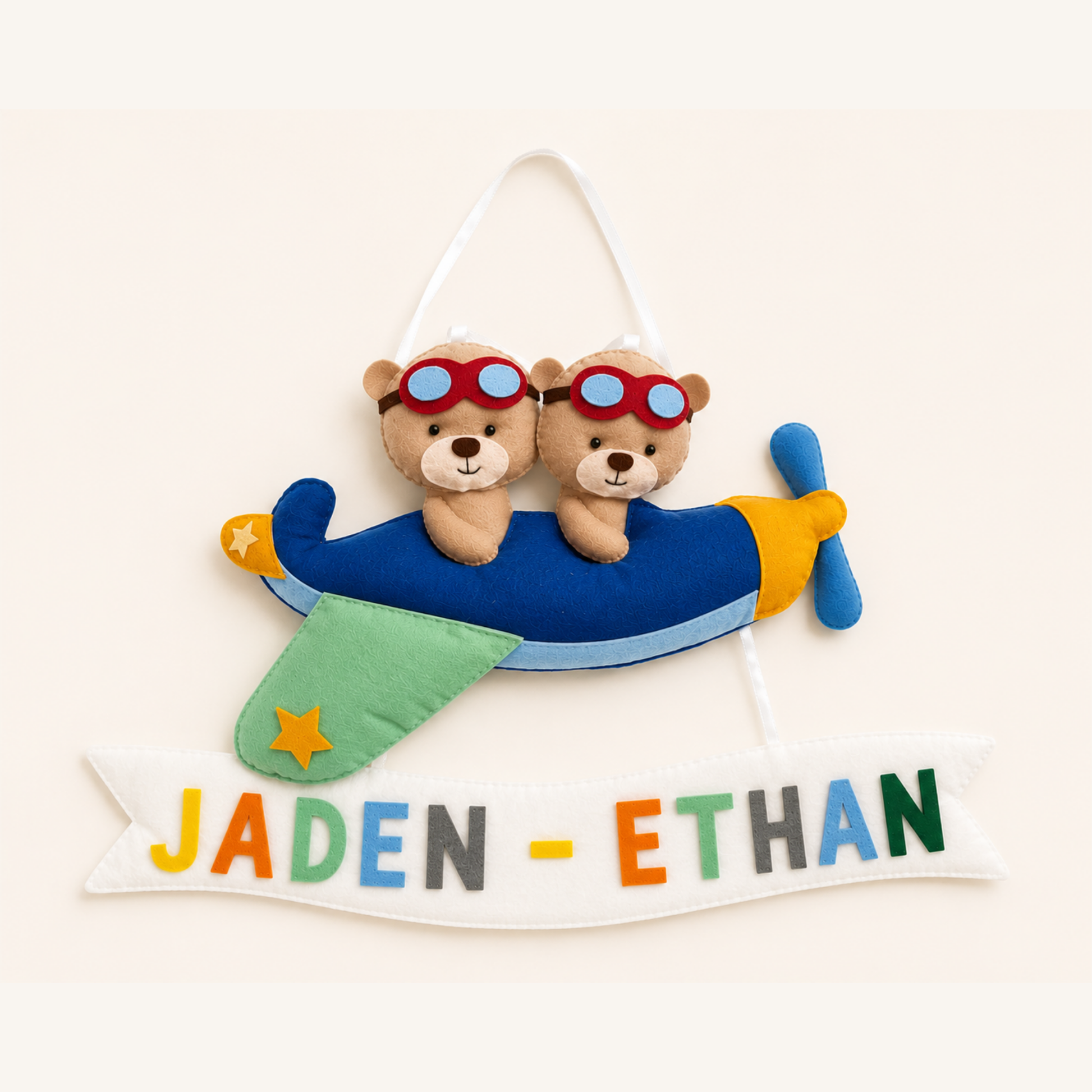 Plush airplane with teddy bears wearing goggles, hanging above a banner with names 'Jaden' and 'Ethan'.