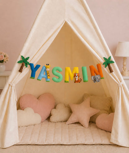 Children's play tent with colorful name garland spelling 'YASMIN' and various felt toys inside.