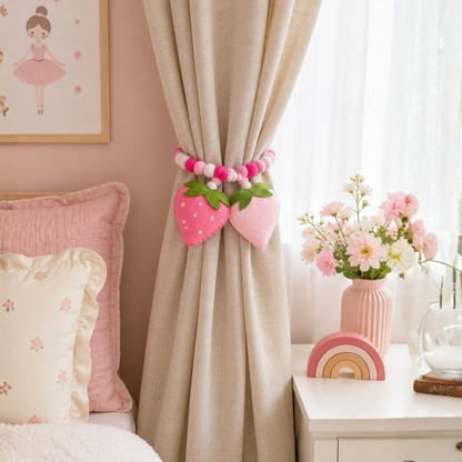 Decorative pink strawberry curtain tiebacks in a child's bedroom with floral arrangement and pillows.