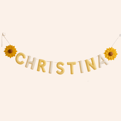 Name 'Christina' spelled out with yellow and white name garland, flanked by two sunflowers on a beige background.