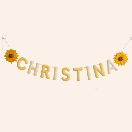 Name 'Christina' spelled out with yellow and white name garland, flanked by two sunflowers on a beige background.