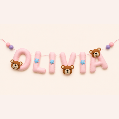 Name 'OLIVIA' spelled out with teddy bear-themed letters on a light pink background name garland