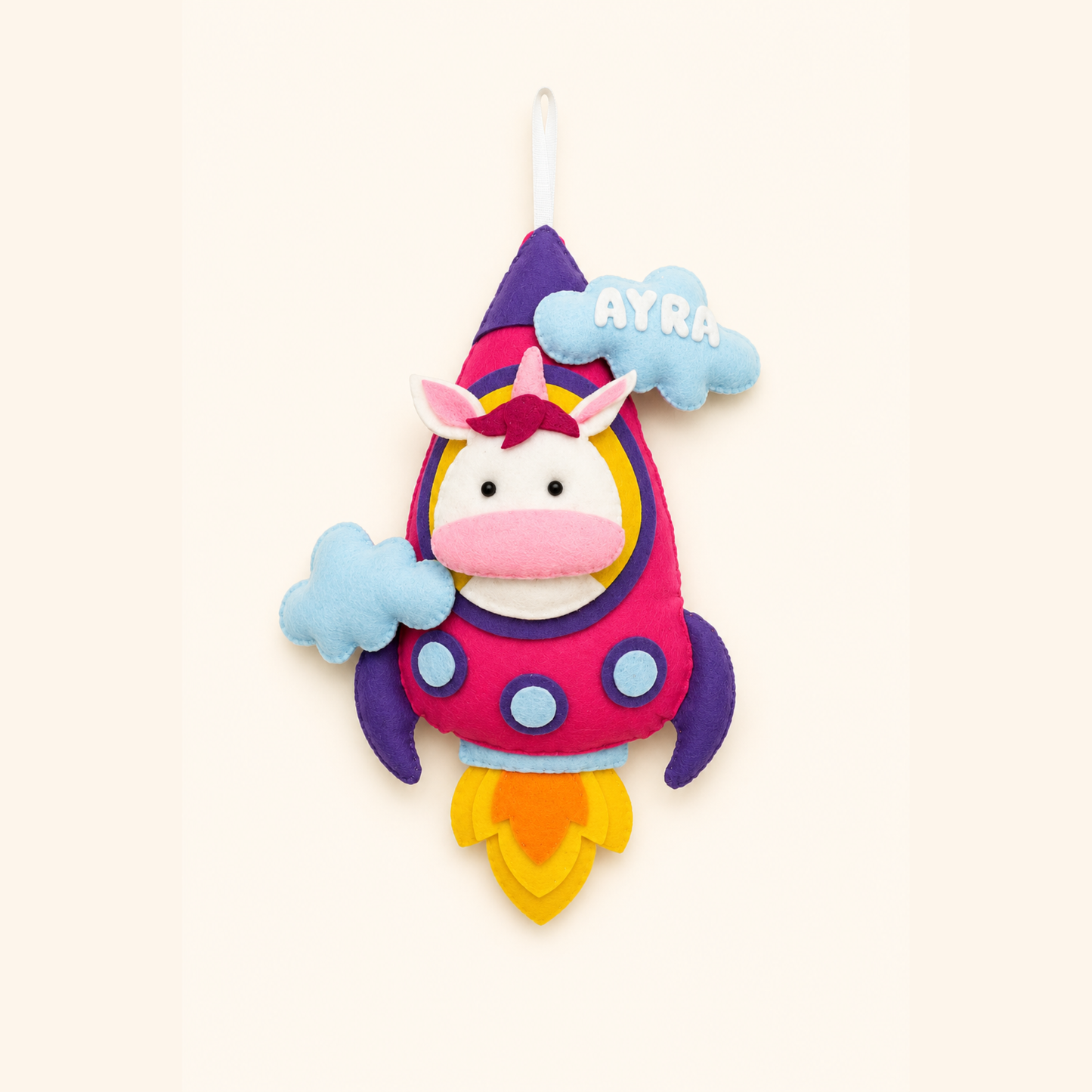 Colorful unicorn plush toy with a rocket design on a light beige background