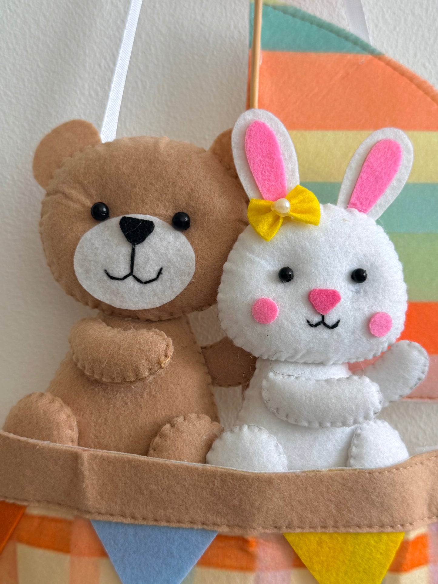 Stuffed teddy bear and rabbit in a boat with a colorful striped background