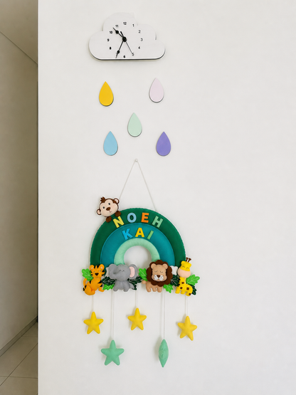 Decorative wall hanging with colorful raindrop shapes and animal figures on a white wall.